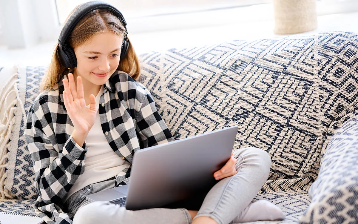 Young girl attending a virtual therapy session from home using a laptop and headphones.